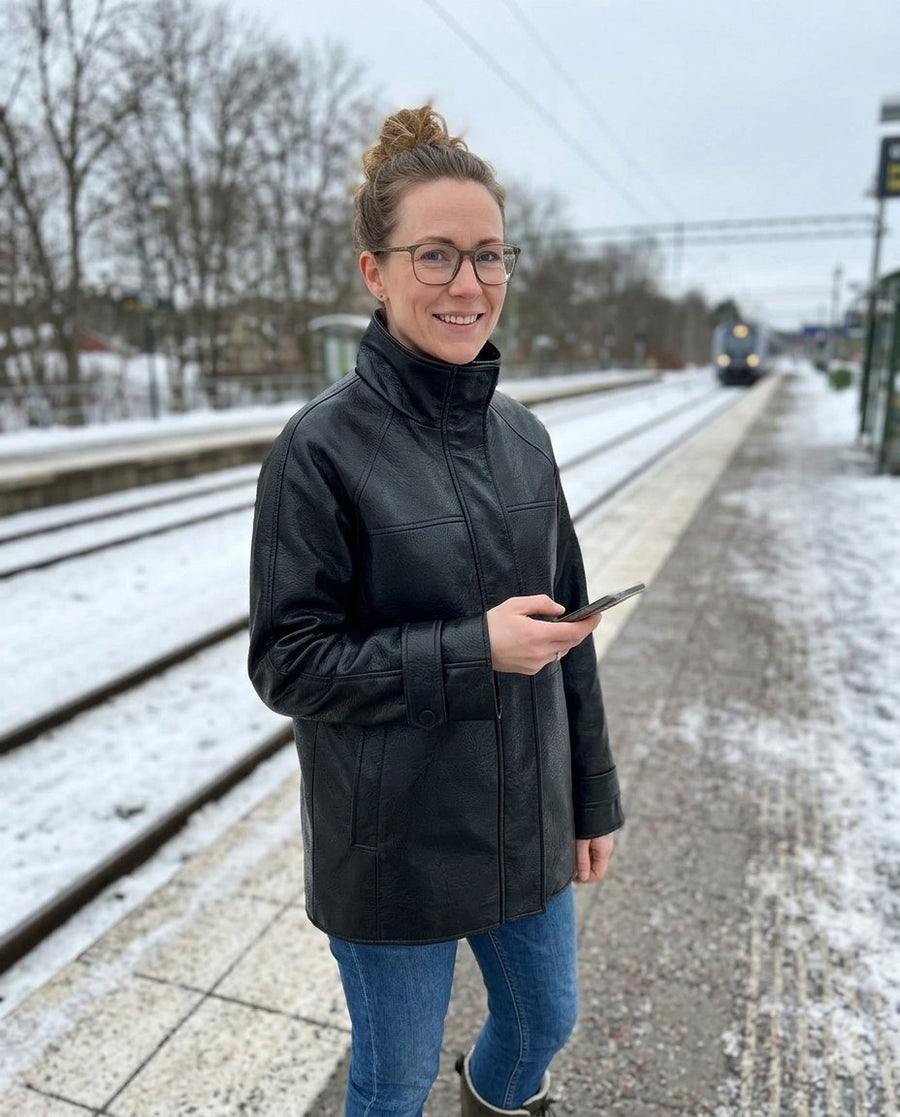 Astrid, jacka i skinnimitation med hög krage för dam i svart, stylinginspiration på en perron