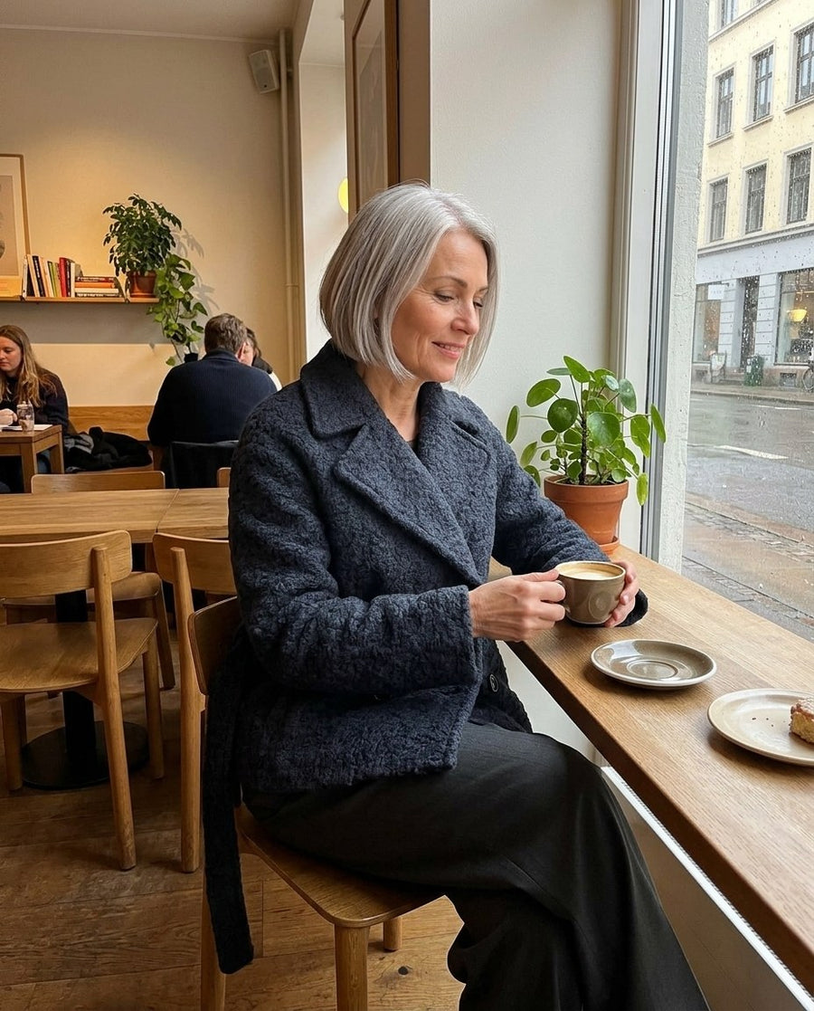 Vilda, kort dubbelknäppt kappa med slagkrage för dam i mörkblå, stylinginspiration på ett kafé