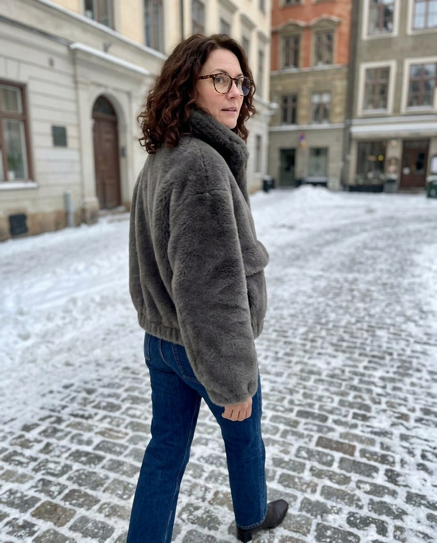 Hedda, kort jacka i mjuk fuskpäls för dam i grå, stylinginspiration på en snöig gata