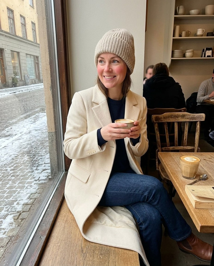 Majken, lång figursydd kappa för dam i ljusbeige, stylinginspiration på ett kafé