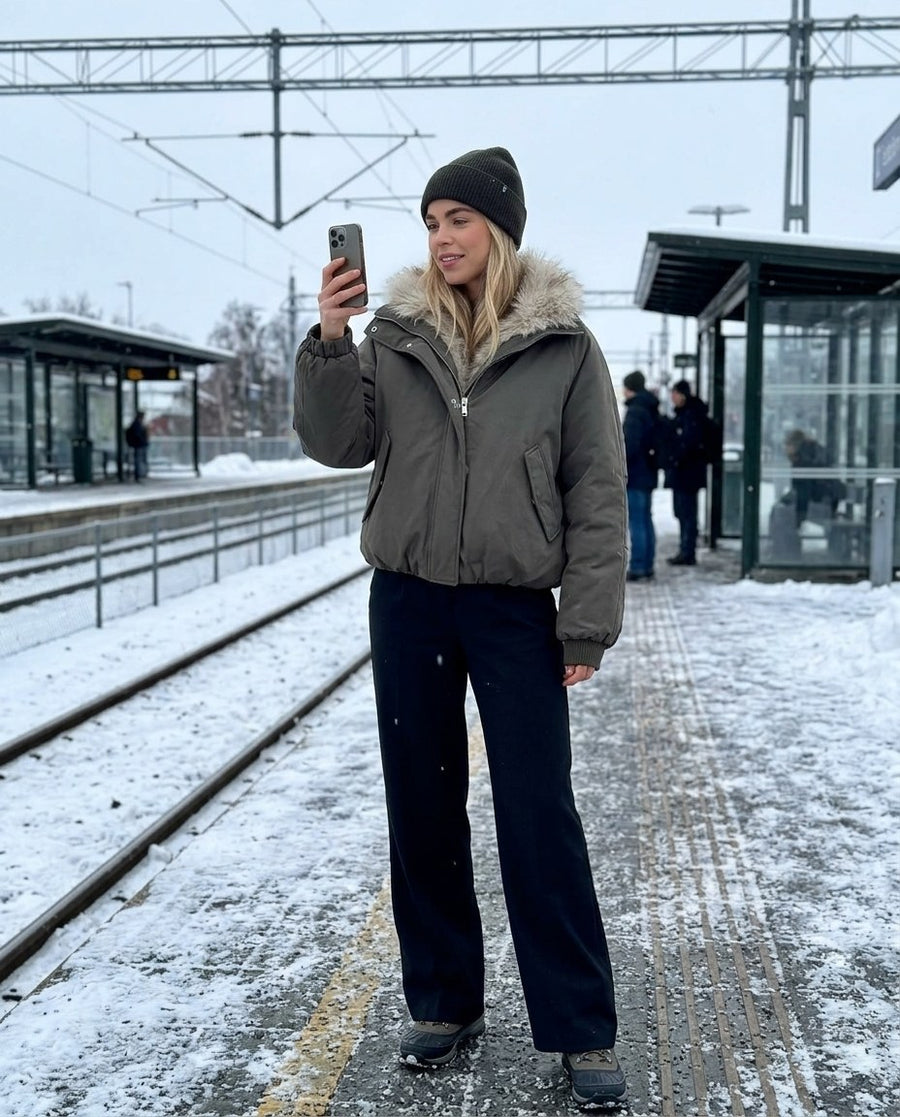 Svea, vadderad bomberjacka med hög krage för dam i mörk olivgrön, stylinginspiration på en perron